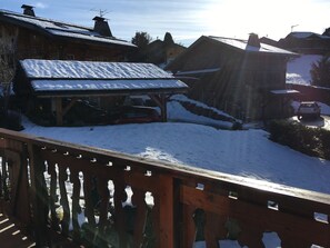 A wooden building with a snow-covered roof, a covered area, and a car parked nearby. - 5-bedroom chalet for 10 with private parking (Arâches-la-Frasse)