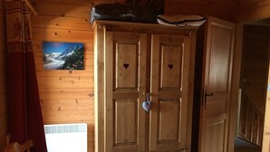 Una habitación de madera con un armario grande, una cama y una ventana con un paisaje de montaña.