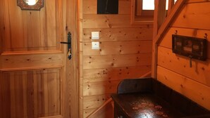 Un interior de madera con una puerta, un interruptor de luz en la pared y un banco.