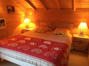 A cozy wooden room with a large bed, two bedside tables with lamps, and a framed picture on the wall. - 5-bedroom chalet for 10 with private parking (Arâches-la-Frasse)