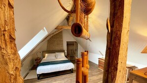 Ein gemütliches Schlafzimmer im Dachgeschoss mit schrägen Wänden, einem hölzernen Bett und rustikalem Dekor.