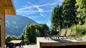 Una terraza de madera con muebles de exterior con vistas a un paisaje montañoso.