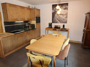 A modern kitchen with wooden cabinets, a black countertop, and a dining area with a wooden table and yellow chairs. - Central apartment 2 rooms, Arâches, 5 guests, parking, wifi (Arâches-la-Frasse)