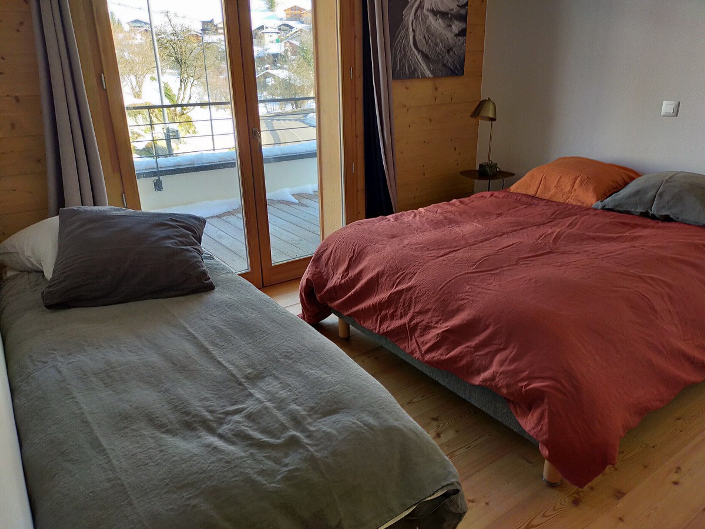 Une chambre avec deux lits, une fenêtre donnant sur l’extérieur et une lampe sur une table de chevet.