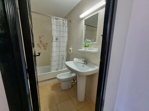 Ein Badezimmer mit Dusche, Toilette, Waschbecken und Spiegel.