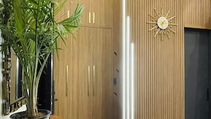 A modern interior with wooden cabinetry, a potted plant, a unique wall clock, and a small bench. - The Roncy Den ~a boutique laneway house (Toronto)