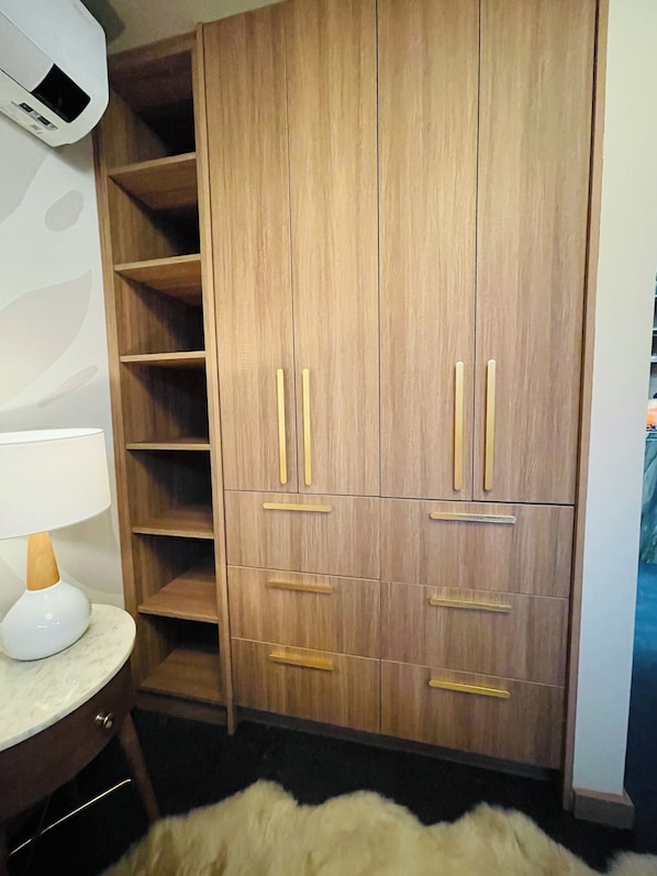A wooden wardrobe with multiple shelves and drawers, a white lamp, and a fluffy rug.