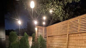 An outdoor patio with a wooden table and chairs, surrounded by a wooden fence and potted plants. - The Roncy Den ~a boutique laneway house (Toronto)