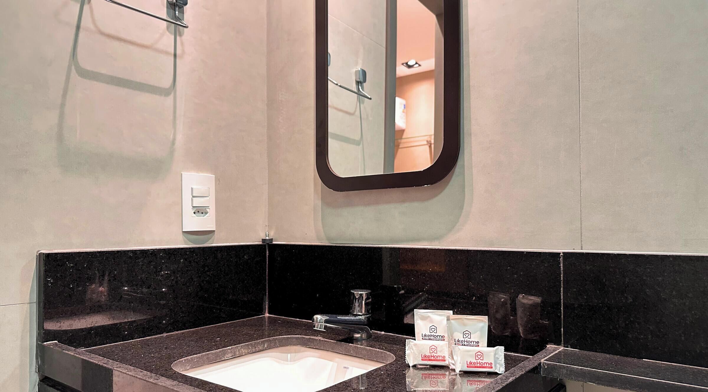Un baño con lavamanos, espejo y dispensador de jabón.