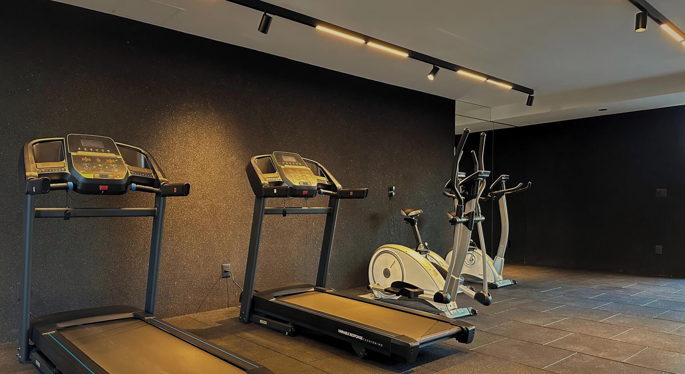 A gym with treadmills, an elliptical, and a stationary bike.