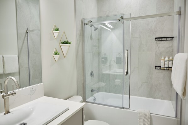 Une salle de bain moderne avec une douche à parois de verre, un lavabo blanc et des toilettes.