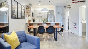 A modern kitchen with a dining area, featuring a wooden table, black chairs, and pendant lighting. - Ripper Retreat - Modern Condo w/hot tub 5 minutes to Revelstoke Mountain Resort! (Revelstoke)