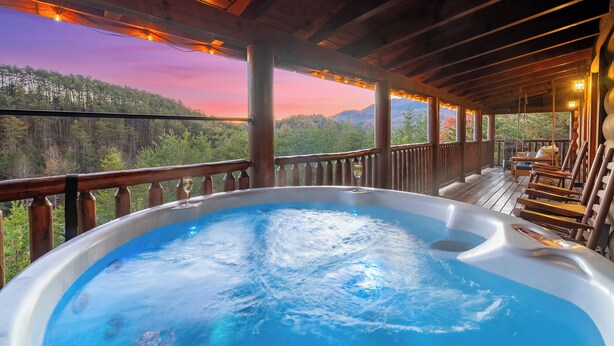 Ein Whirlpool mit einer Holzterrasse und Blick auf einen bewaldeten Gebirgszug.