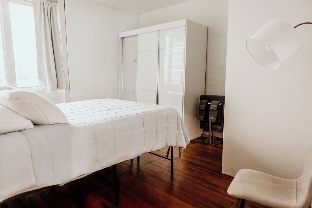 Une chambre à coucher avec un lit, une armoire, une chaise et une lampe.