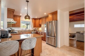 Una cocina moderna con armarios de madera, electrodomésticos de acero inoxidable y una isla grande con taburetes de bar.