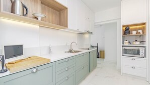 Een moderne keuken met lichtgroene kastjes, een witte werkblad en ingebouwde apparatuur, waaronder een waterkoker, broodrooster en oven.