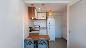 A compact kitchen with a wooden table, two chairs, a sink, and a refrigerator. - Portal dos Mares - Beira-Mar Tamandaré (Tamandaré)