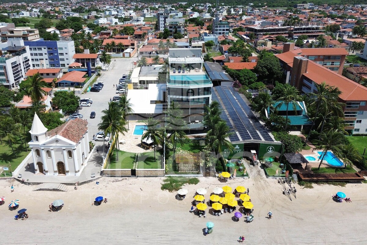 A coastal town with a prominent church, a hotel with solar panels, and a beach area with umbrellas.