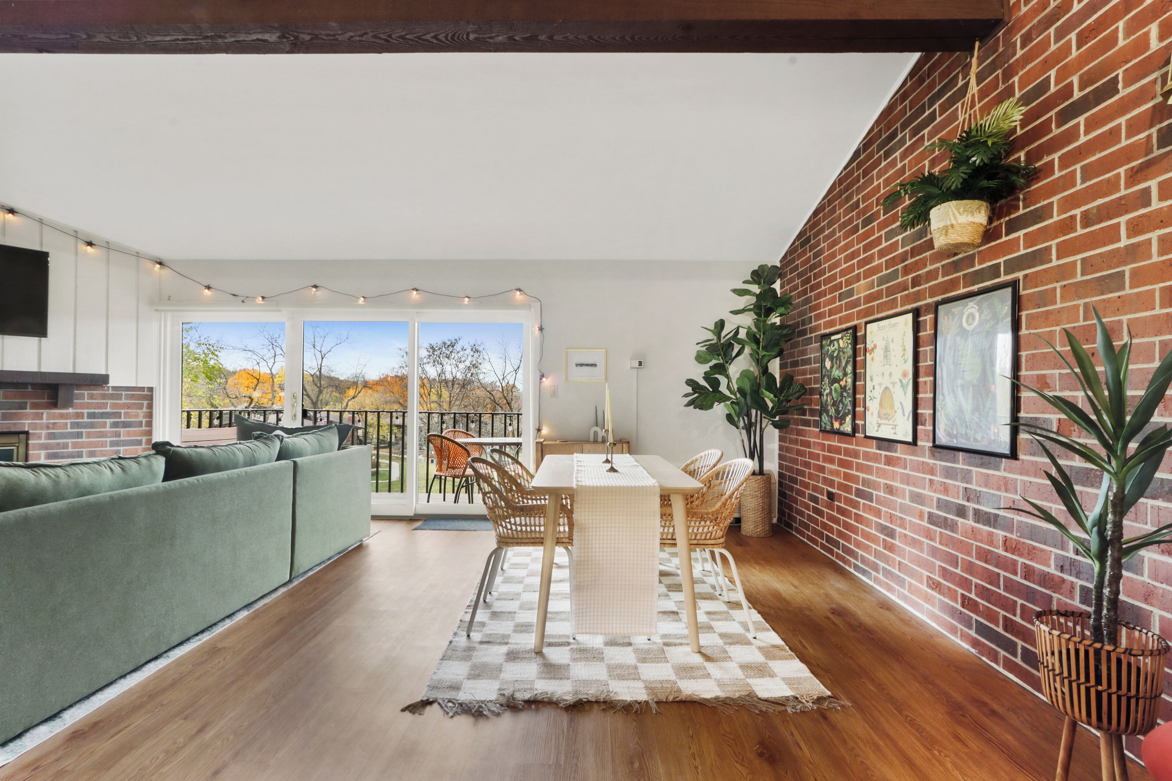 Een moderne woonkamer met een groene bank, een eettafel met stoelen en een geruit vloerkleed.
