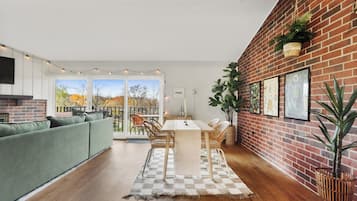 Een moderne woonkamer met een groene bank, een eettafel met stoelen en een geruit vloerkleed.