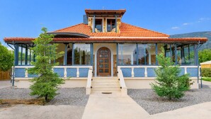 A two-story house with a red-tiled roof, large windows, and a front porch. - Villa Psani Beachfront Escape With Garden (Nafpaktos)