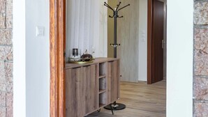 A hallway with a wooden archway, a coat rack, and a wooden console table with decorative items. - Villa Psani Beachfront Escape With Garden (Nafpaktos)