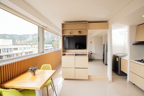 Une cuisine moderne équipée d’un four encastré, d’un réfrigérateur et d’un coin repas avec une table et des chaises.