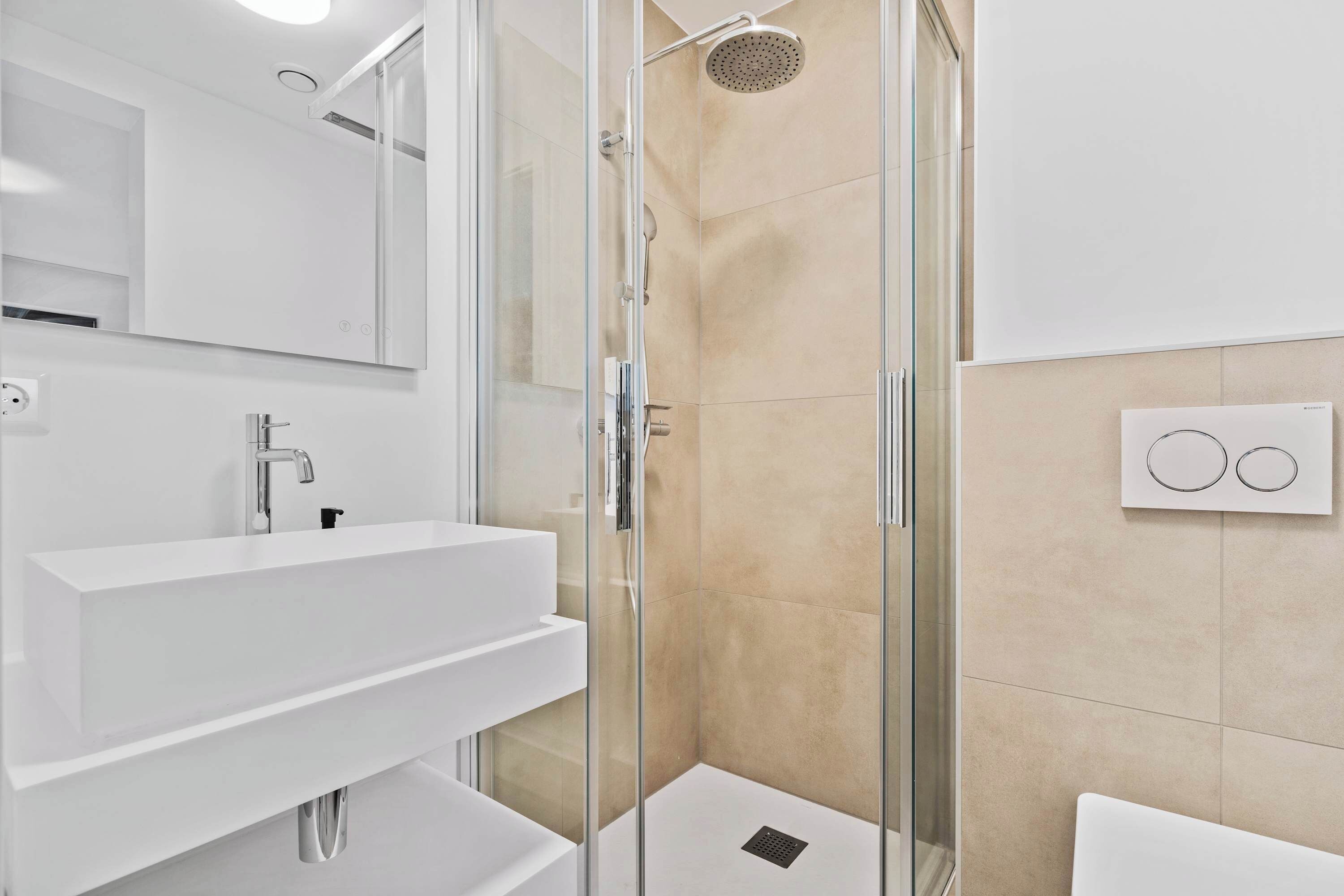 A modern bathroom with a glass-enclosed shower, a white sink, and a large mirror.
