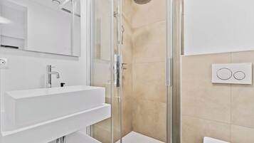 A modern bathroom with a glass-enclosed shower, a white sink, and a large mirror.