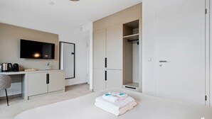A modern hotel room with a bed, a desk with a flat-screen TV, a wardrobe, and a mirror. - Connect, Relax, and Unwind in Premium Coliving (Luxembourg)