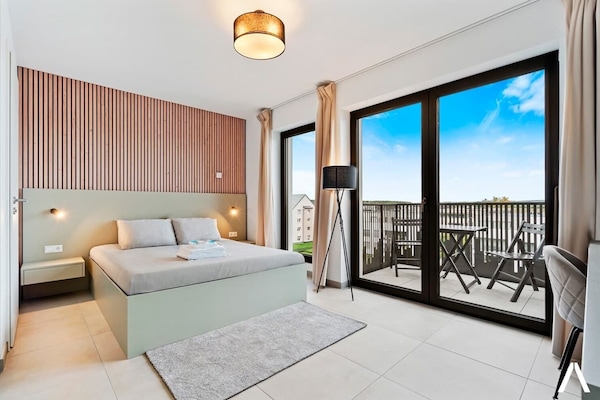 Cozy Living and Sleeping Area – Relax in a comfortable space with a plush queen-sized bed and elegant wooden accent wall.