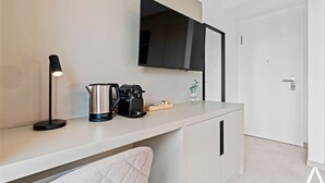 A modern kitchen with a countertop, a kettle, a coffee maker, and a wall-mounted TV. - Connect, Relax, and Unwind in Premium Coliving (Luxembourg)