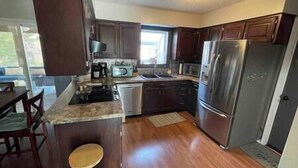 A compact kitchen with dark wood cabinets, stainless steel appliances, and a small island with seating. - Pool! Arcade! Theatre Room! Firepit! 4 BR (Lincoln)