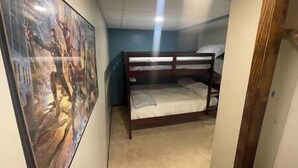 A room with a bunk bed, a poster on the wall, and a door leading to another room. - Pool! Arcade! Theatre Room! Firepit! 4 BR (Lincoln)