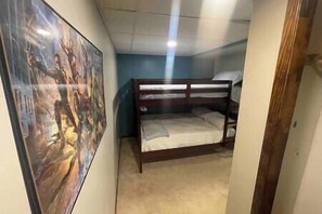 Ein Zimmer mit einem Etagenbett, einem Poster an der Wand und einer Tür zu einem anderen Raum.
