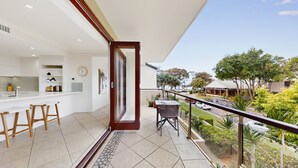 A modern kitchen with white cabinets, a built-in oven, and a dining area with wooden stools. - Beautiful and spacious 3 bedroom apartment (Noosaville)