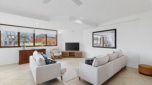 A modern living room with a sofa set, a TV, and a wooden cabinet. - Beautiful and spacious 3 bedroom apartment (Noosaville)