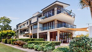 A modern multi-story residential building with balconies, large windows, and a well-maintained garden. - Beautiful and spacious 3 bedroom apartment (Noosaville)