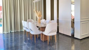 Un espace repas moderne avec une table ronde, des chaises blanches et un vase de fleurs.