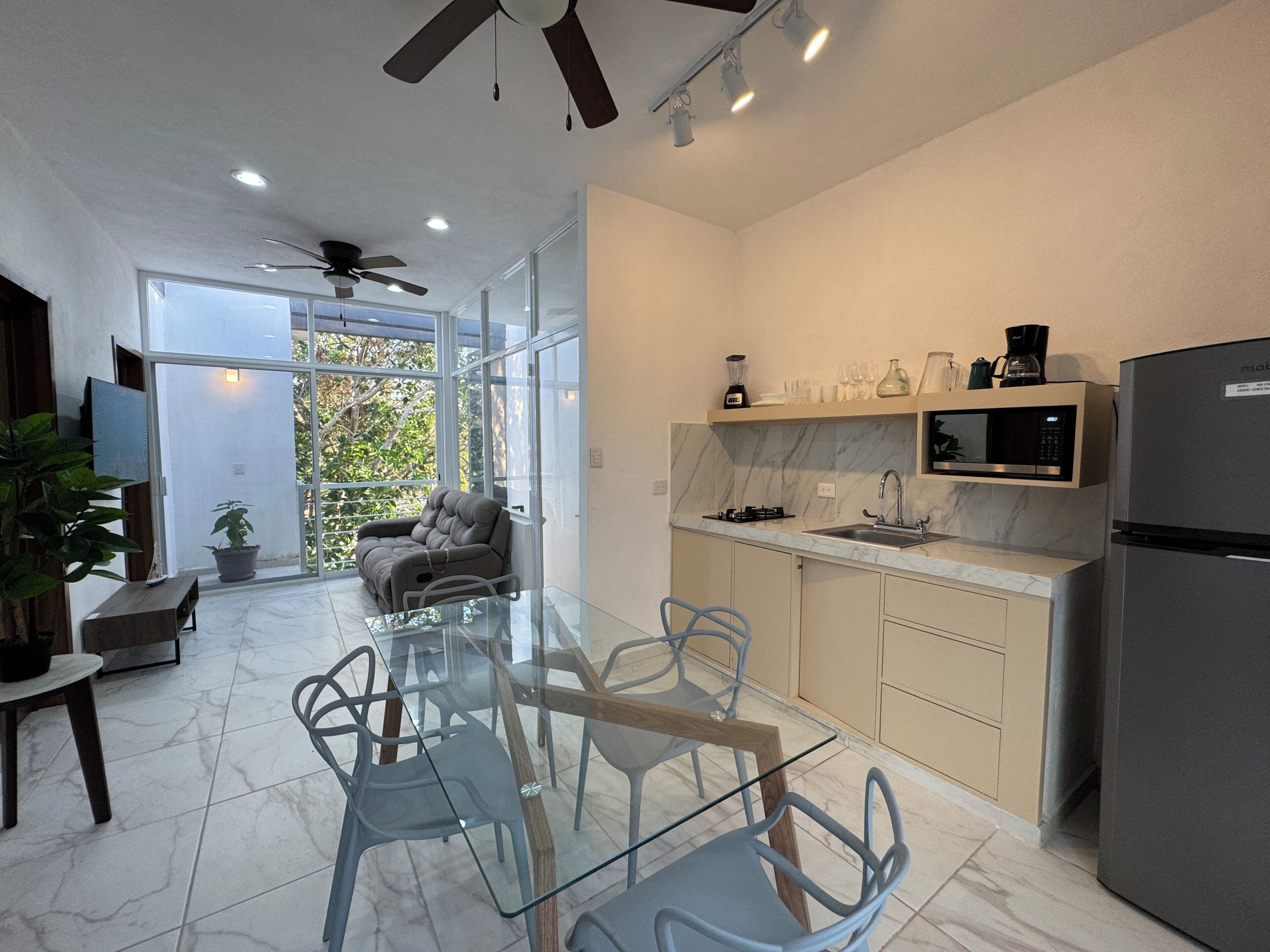 Una cocina moderna con una mesa de vidrio, un sofá y un refrigerador.