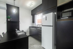 A modern kitchen with dark cabinetry, a built-in oven, and a refrigerator. - Apt 1 Bedroom 220 m From the Beach Cdk0011 (Porto Seguro)
