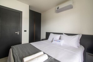 A modern hotel room with a large bed, a dark wardrobe, and a wall-mounted air conditioner. - Apt 1 Bedroom 220 m From the Beach Cdk0011 (Porto Seguro)