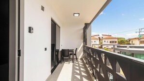 Un balcone con vista sulle case vicine, una porta e un piccolo finestrino.