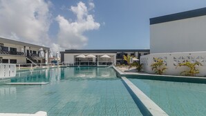 Una piscina con acqua cristallina, circondata da un edificio bianco con molte finestre e un balcone.