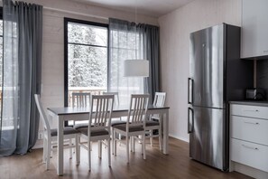 Eine moderne Küche mit einem Edelstahl-Kühlschrank, einem Esstisch mit Stühlen und einem Fenster mit Vorhängen.
