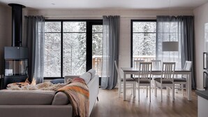 En moderne stue med pejs, spiseplads og store vinduer med udsigt til sne.