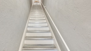 Una escalera con paredes blancas y escalones de madera.