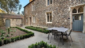 Un bâtiment en pierre doté d’une cour, d’une table à manger et de chaises.