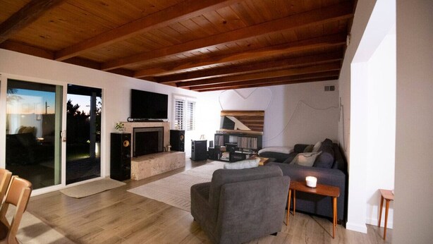 A spacious living room with a fireplace, a television, and a comfortable seating area. - The Atlas House | Stay, Surf, and Spin | San Diego (San Diego)