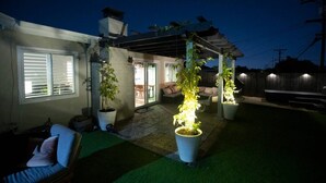 A covered patio area with potted plants and a seating area. - The Atlas House | Stay, Surf, and Spin | San Diego (San Diego)